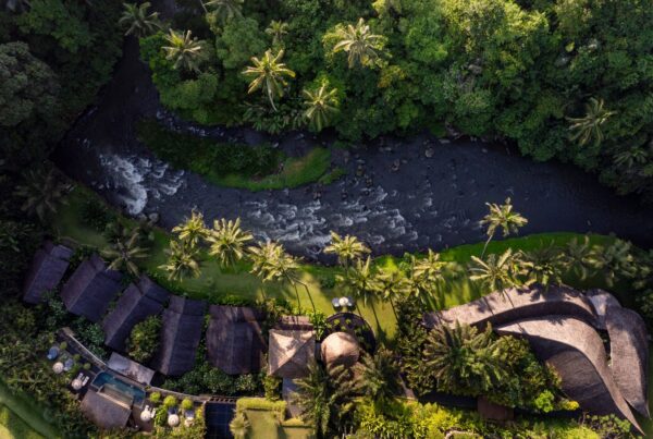 Aerial drone view of a private luxury villa at Mandapa, a Ritz-Carlton Reserve in Ubud, nestled among lush, verdant terraced rice paddies.