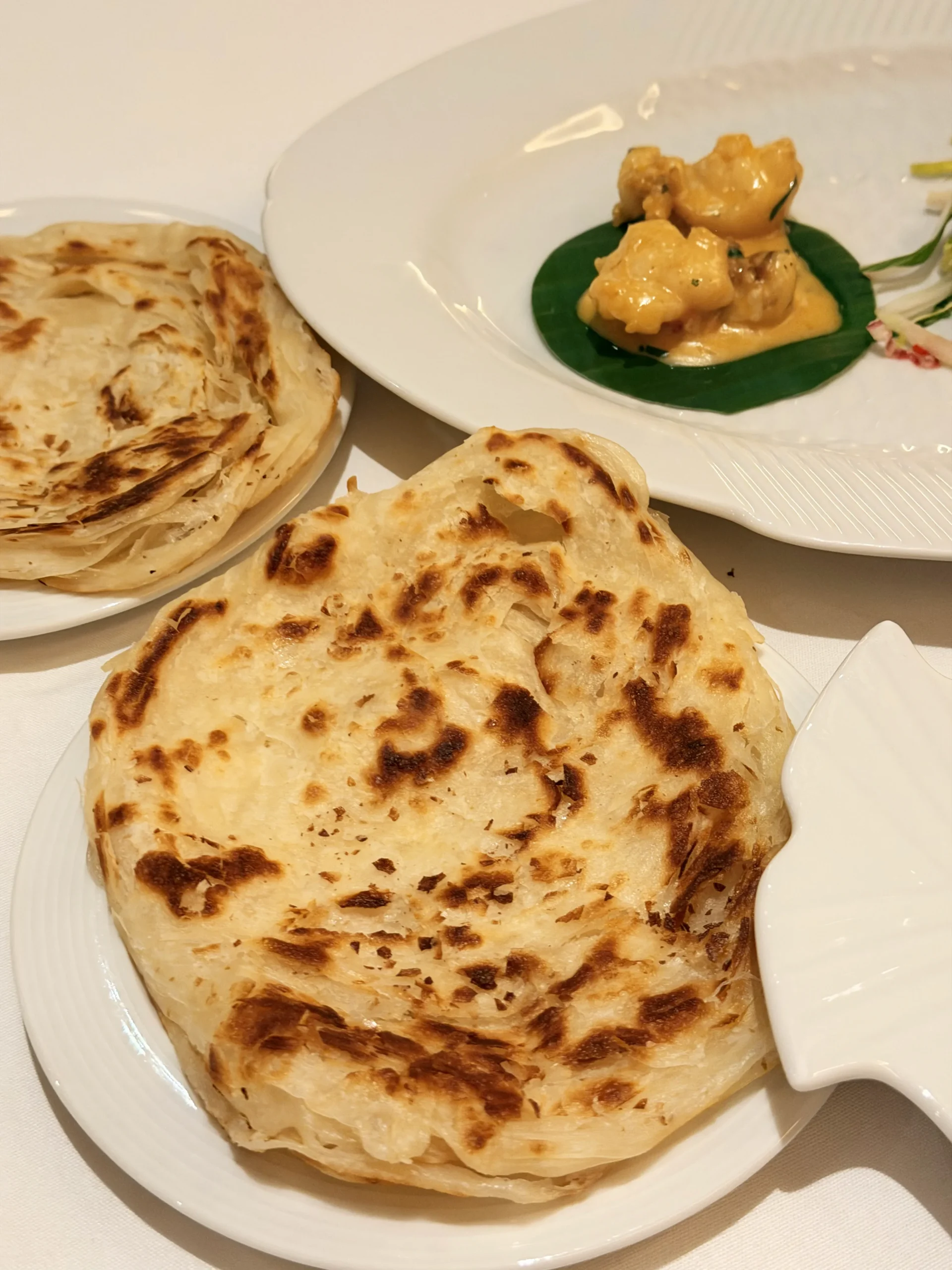 Flaky, layered Malabar paratha cooked on a skillet with pure ghee at Quilon London.