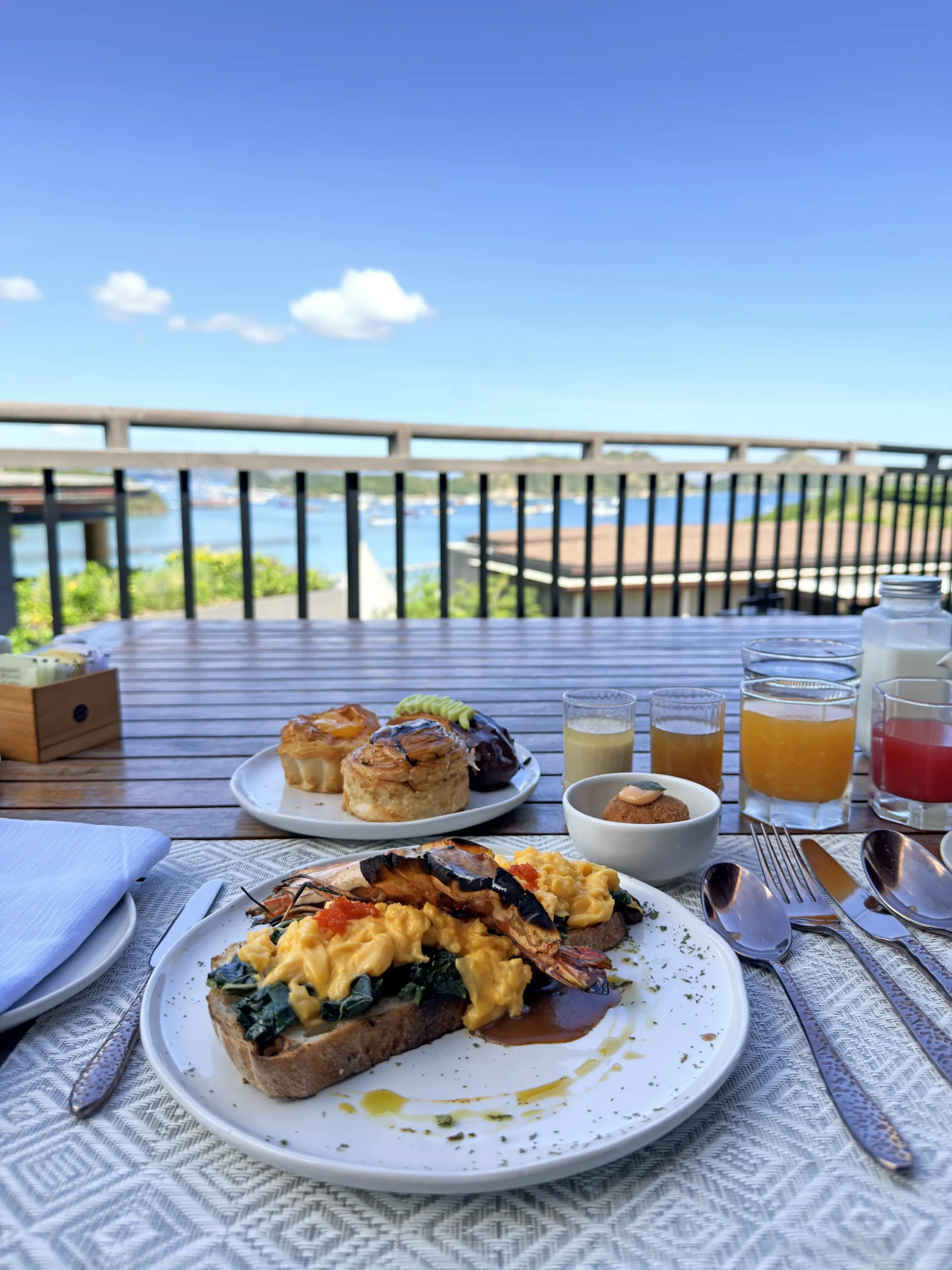 Outdoor open-air breakfast dining terrace at Leros, set against a backdrop of panoramic ocean views during the morning.