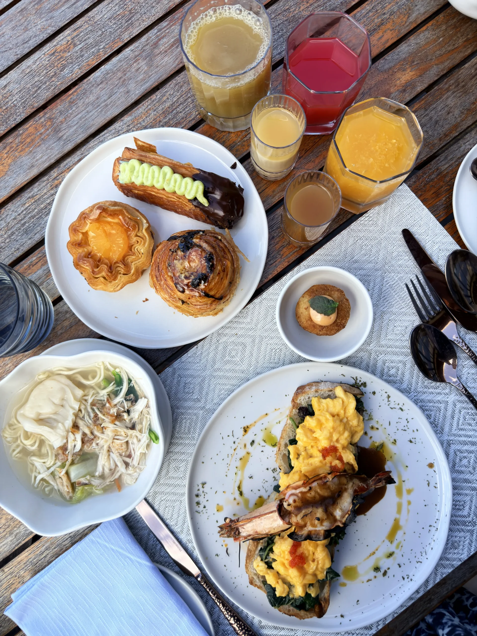 Gourmet breakfast spread featuring scrambled eggs with sautéed prawns, a selection of fresh fruit juices, and golden-brown French toast.
