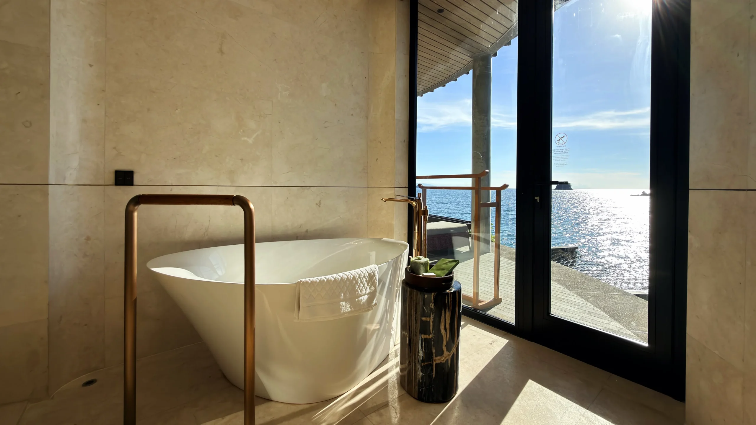 Freestanding deep-soaking bathtub in a Ta'aktana overwater villa with an uninterrupted view of the Indian Ocean.
