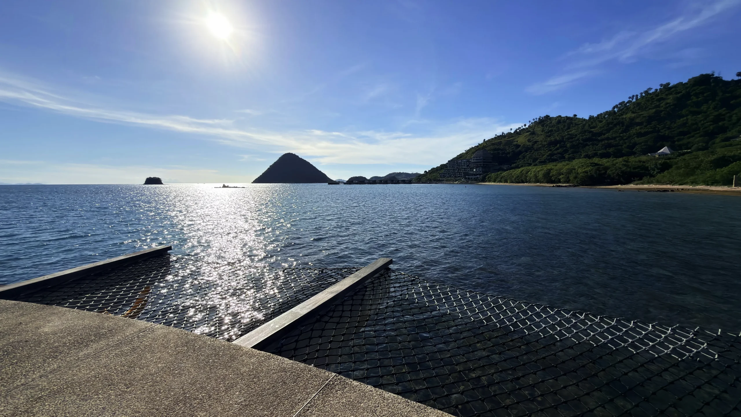 Private sun deck of a Ta'aktana overwater villa, furnished with comfortable lounge chairs and direct step-down access into the calm, crystal-clear water.