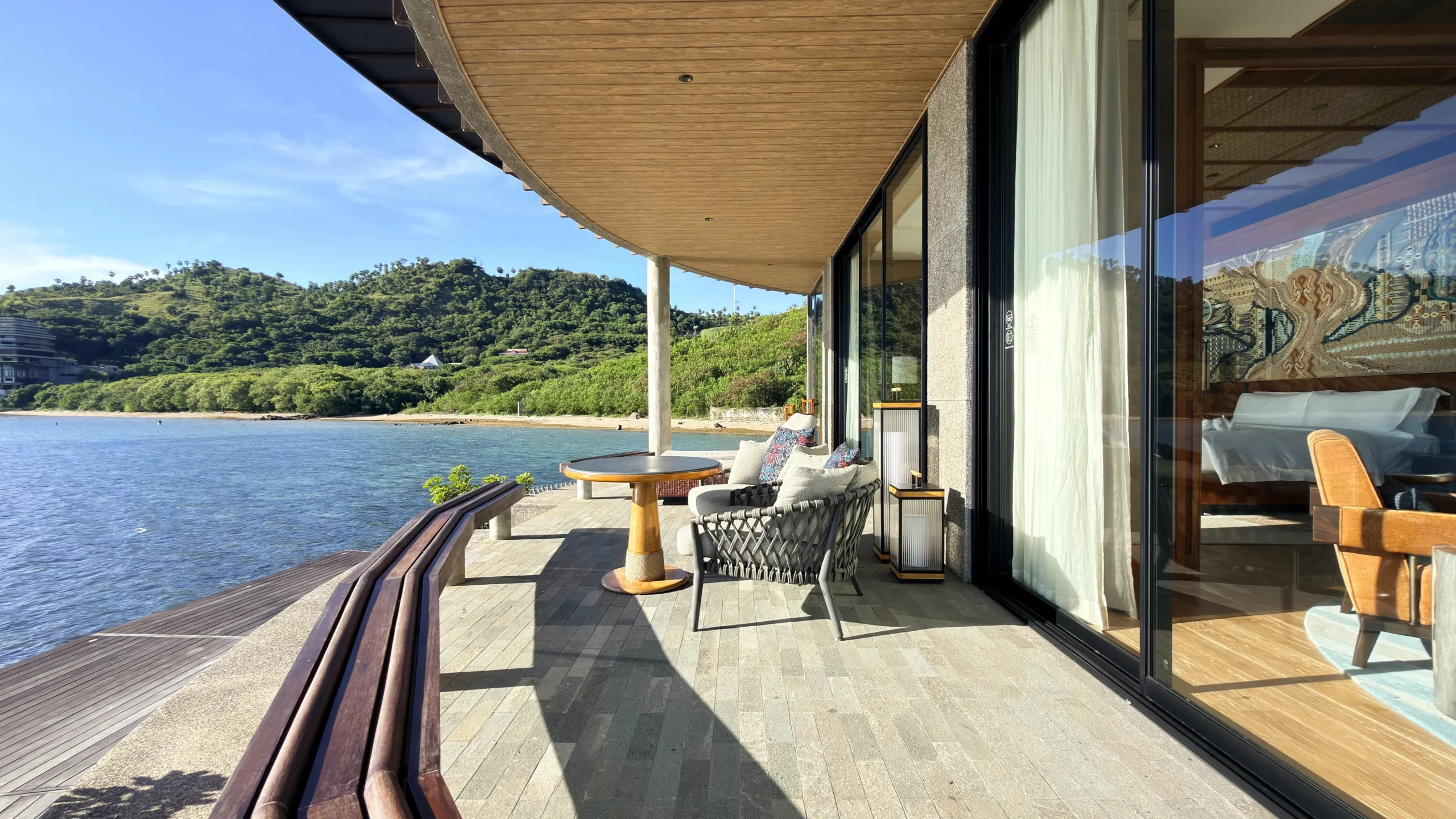 Private sun deck of a Ta'aktana overwater villa, furnished with comfortable lounge chairs and direct step-down access into the calm, crystal-clear water.