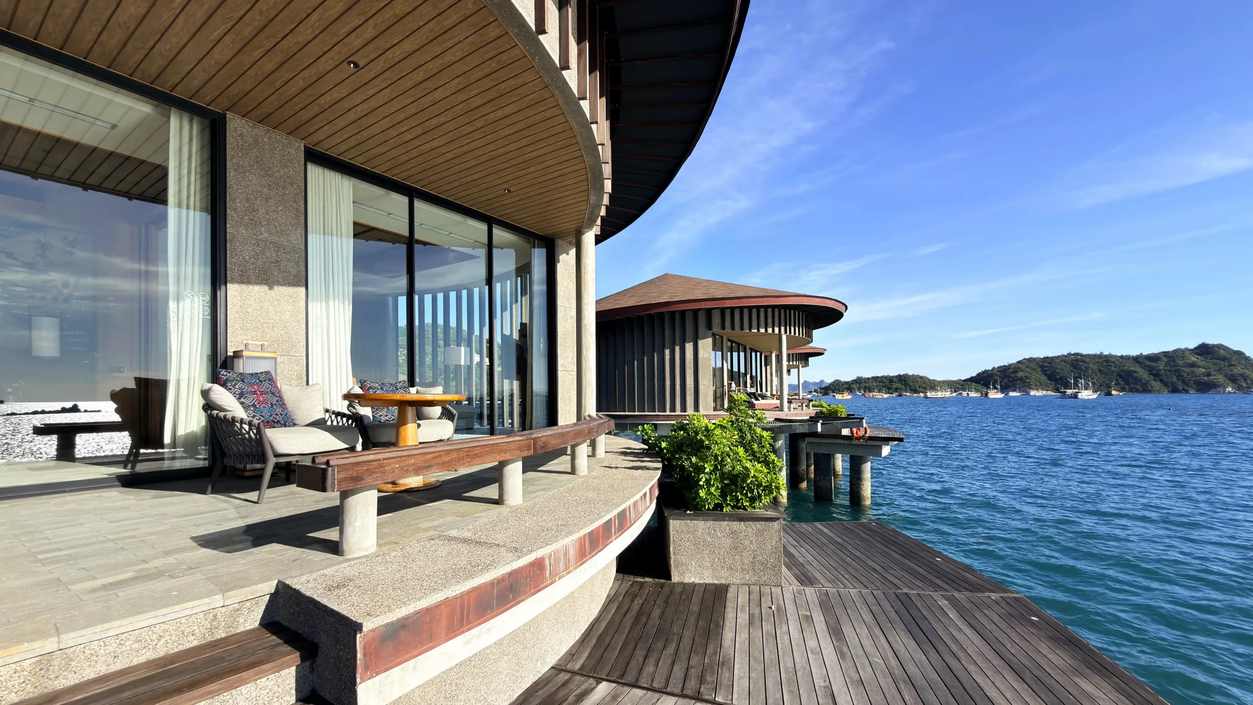 Private sun deck of a Ta'aktana overwater villa, furnished with comfortable lounge chairs and direct step-down access into the calm, crystal-clear water.
