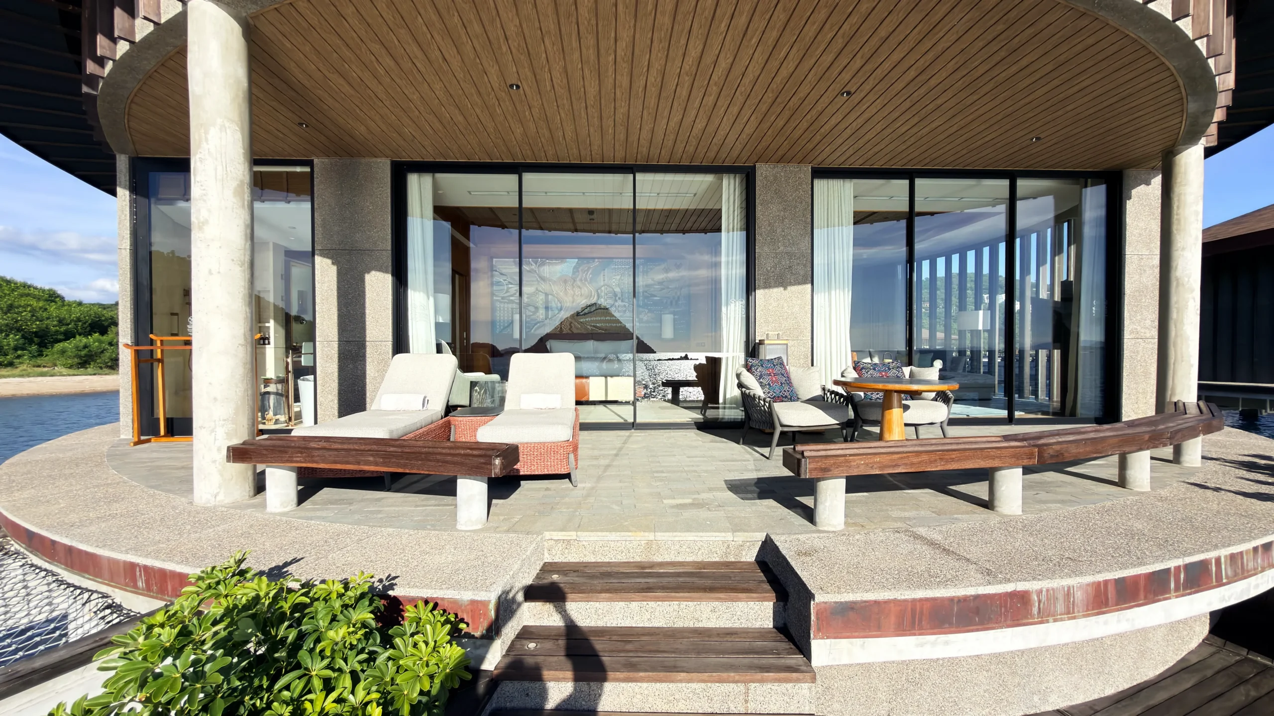 Private sun deck of a Ta'aktana overwater villa, furnished with comfortable lounge chairs and direct step-down access into the calm, crystal-clear water.