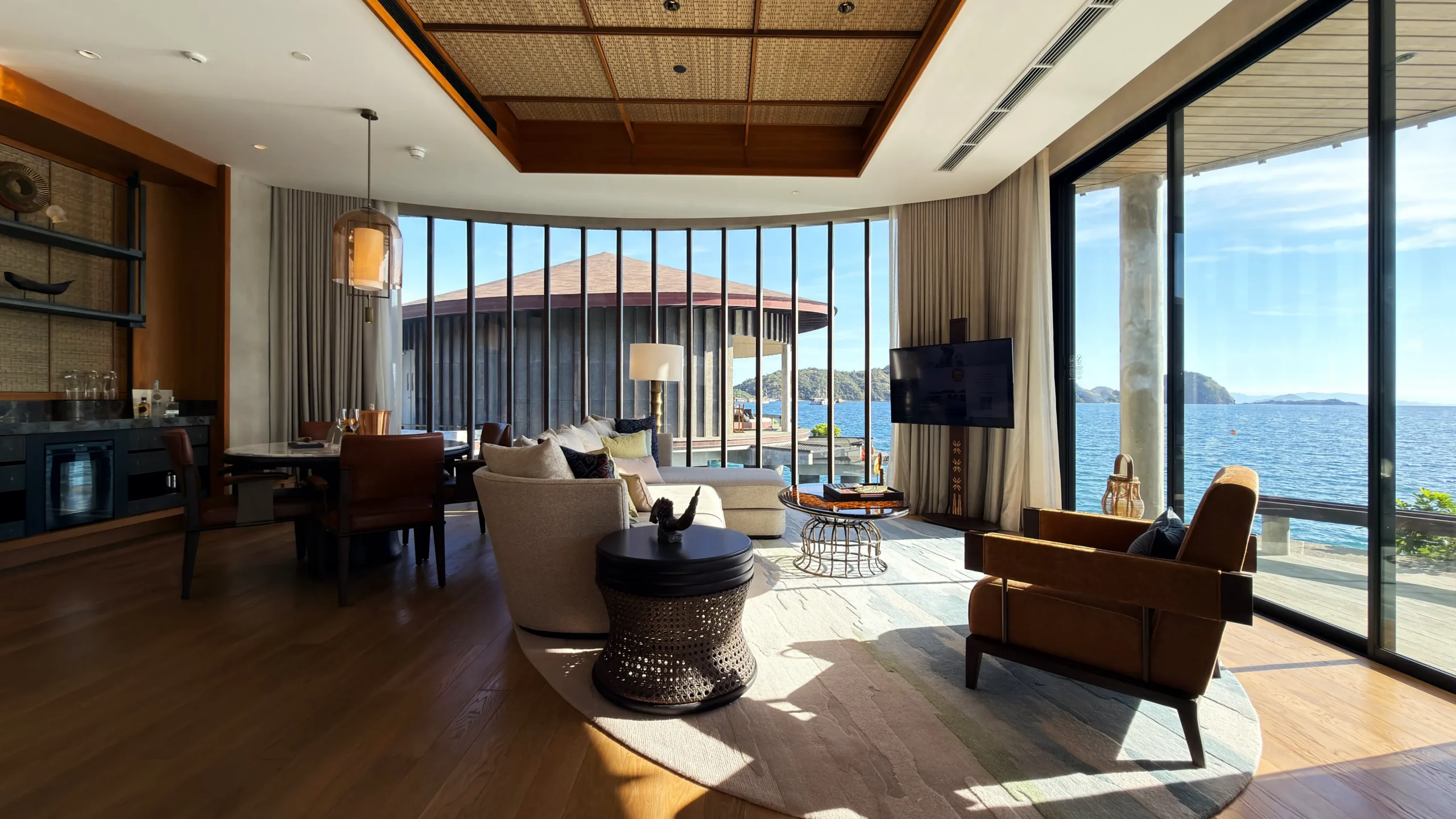 Sunlit living area inside a luxury overwater villa at Ta'aktana, featuring locally inspired decor, high ceilings, and panoramic views of the Flores Sea.