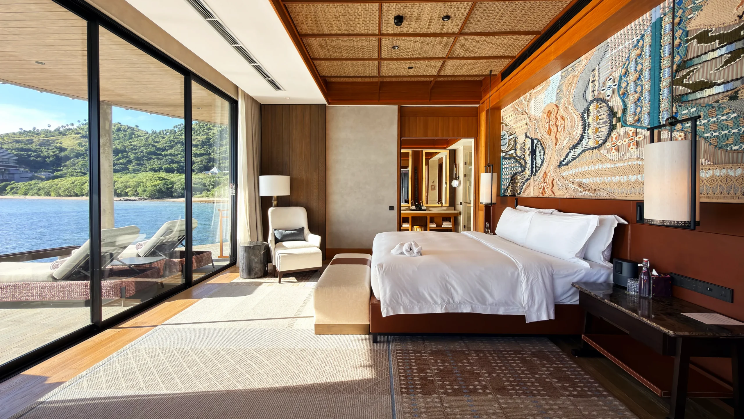Plush master bedroom suite in a Ta'aktana overwater villa, styled with refined craftsmanship, premium linens, and direct views of the turquoise ocean.