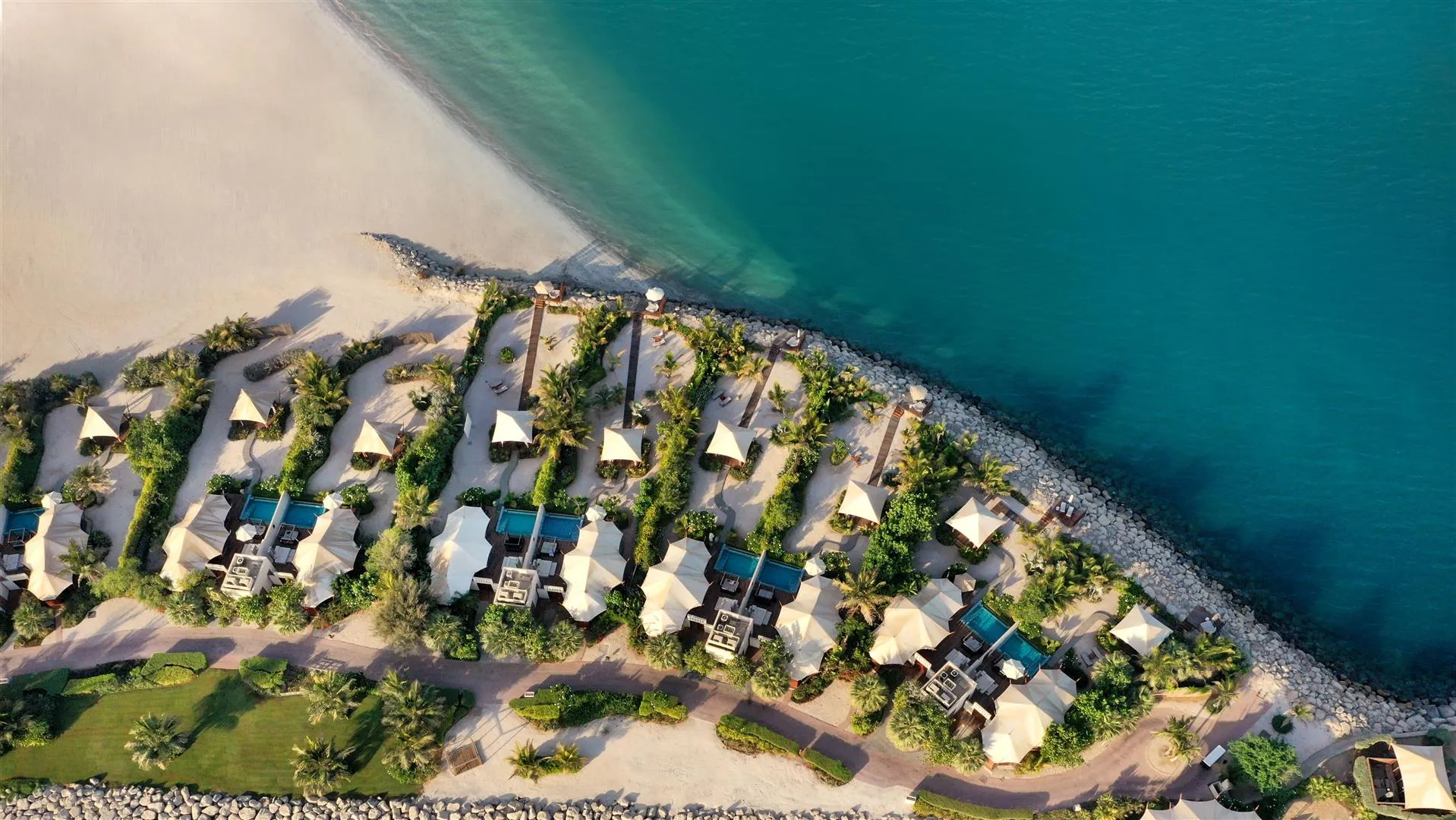 Stunning aerial view of The Ritz-Carlton, Al Hamra Beach in Ras Al Khaimah, showcasing the secluded private villas situated directly on the pristine coastline.
