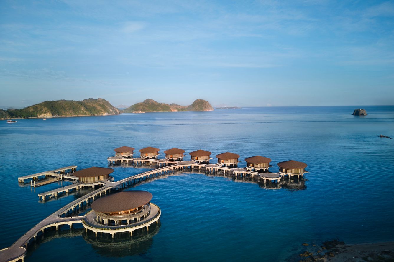 Breathtaking bird's-eye view of the overwater villas at Ta'aktana, a Luxury Collection Resort & Spa, perfectly positioned over the crystal-clear turquoise waters of the Flores Sea.