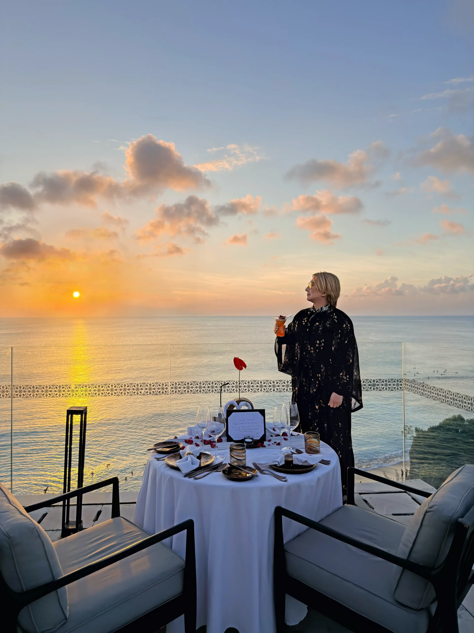 Stefano Malachi taking in the breathtaking golden hour sunset at Jumeirah Bali, framed by the resort's distinctive Hindu-Javanese water palace architecture and the Indian Ocean coastline.