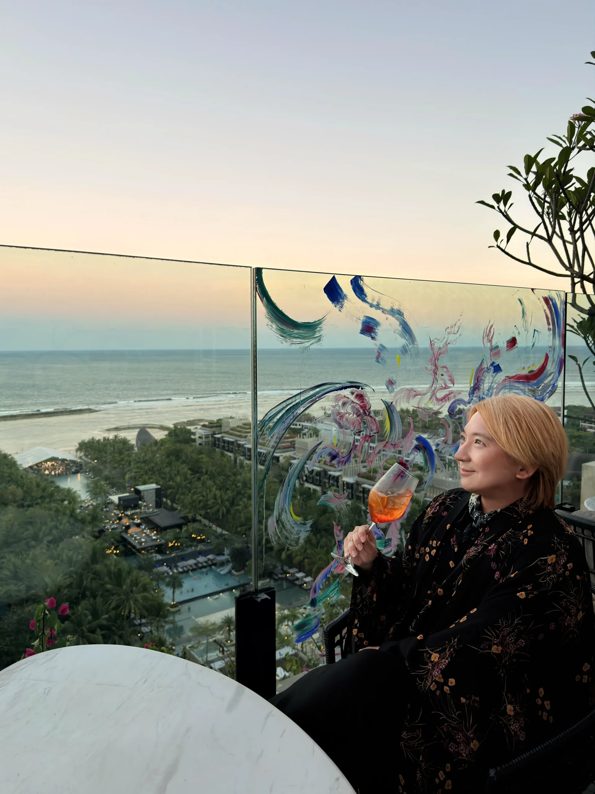 Stefano Malachi enjoying the rooftop sunset hour at L’Atelier by Cyril Kongo, surrounded by vibrant contemporary street art and panoramic ocean views at The Apurva Kempinski Bali.